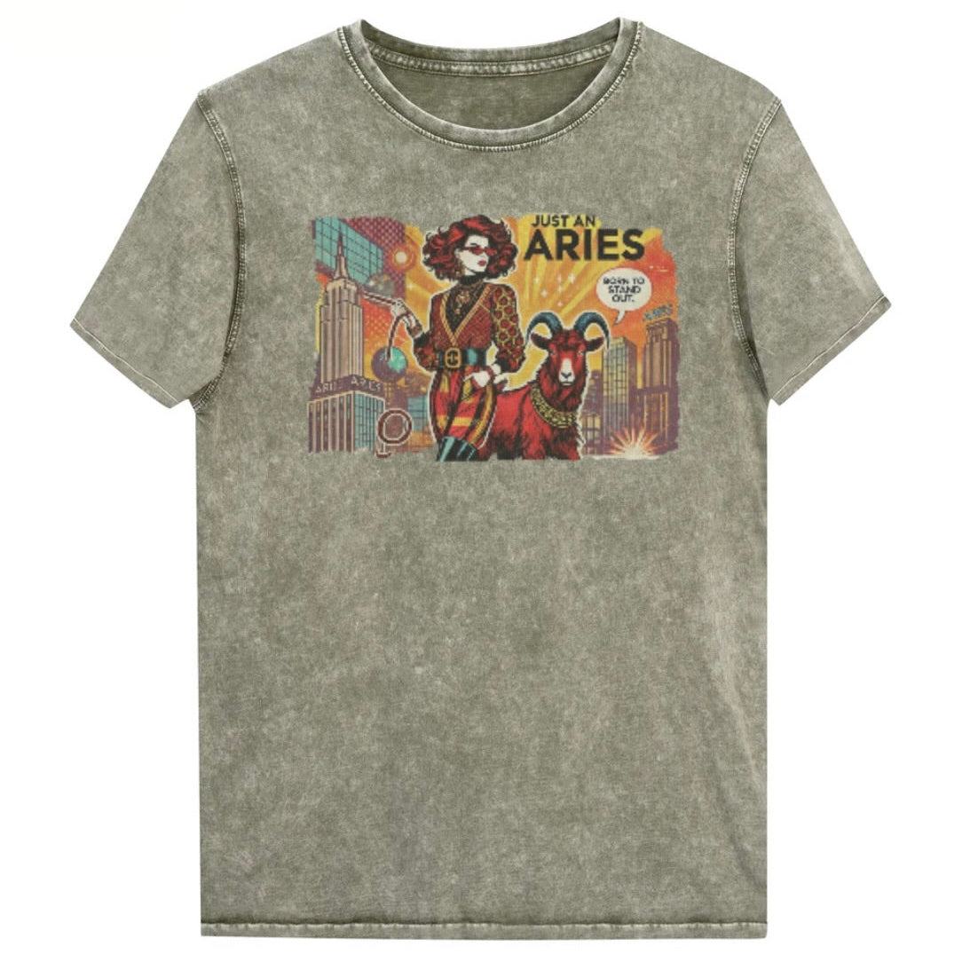 Flatlay of a unisex army green denim wash vintage t-shirt with a retro pop-art Aries graphic featuring a redhead woman, wearing a belted catsuit and high boots with one hand in her pocket, with a ram by her side and a city backdrop, captioned ‘Just an Aries, born to stand out'. Branded RedBlonde on inside neck and right sleeve