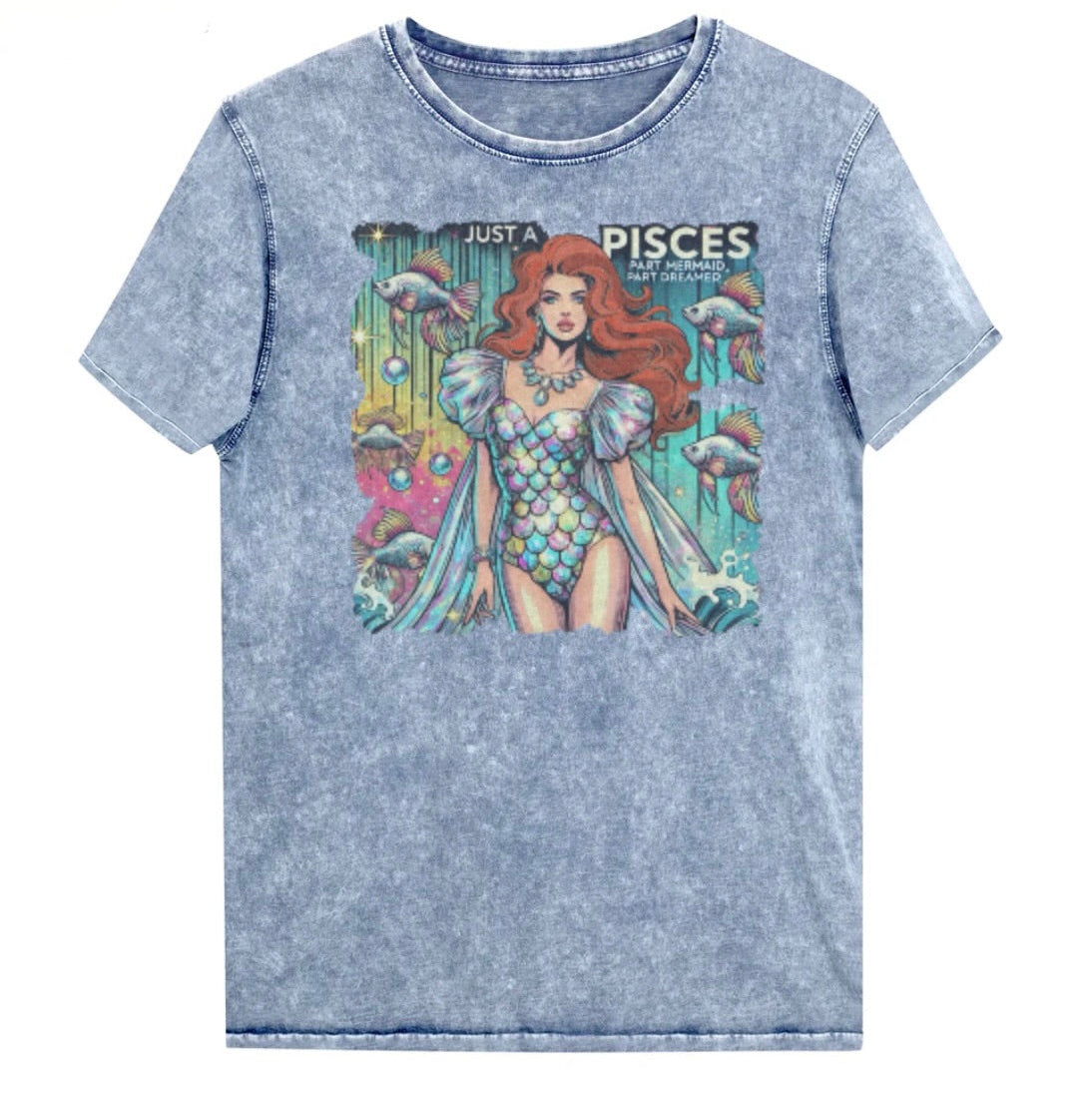 Flatlay of a unisex blue denim wash vintage t-shirt with a retro pop-art Pisces graphic featuring a redhead woman in a fish-scale dress, with fishes and bubbles backdrop, captioned ‘Just a Pisces, Part Mermaid, Part Dreamer'. Branded RedBlonde in red on inside neck and right shoulder
