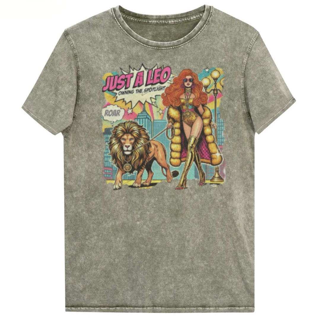 Flatlay of a unisex army green denim wash vintage t-shirt with a retro pop-art Leo graphic featuring a long haired redhead woman in a gold swimsuit, gold over the knee boots, gold medallion and long fur coat, walking a lion on a leash wearing a gold medallion, with a caption bubble 'Roar', with a city and round bulb street lights in the background captioned ‘Just a Leo, Owning the Spotlight'. Branded RedBlonde in red on inside neck and right shoulder