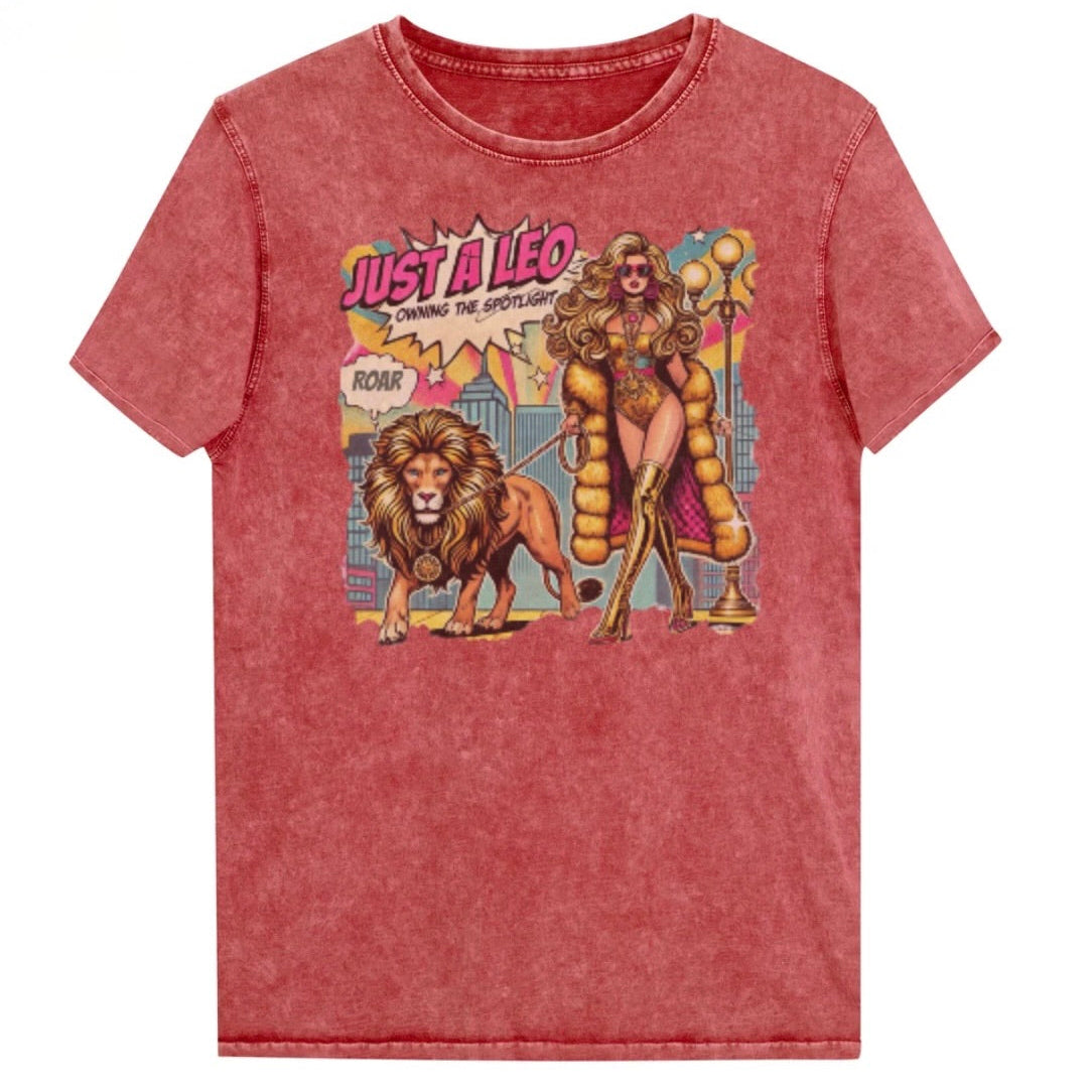 Flatlay of a unisex garnet red denim wash vintage t-shirt with a retro pop-art Leo graphic featuring a long curly haired blonde woman in a gold swimsuit, gold over the knee boots, gold medallion and long fur coat, walking a lion on a leash wearing a gold medallion, with a caption bubble 'Roar', with a city and round bulb street lights in the background captioned ‘Just a Leo, Owning the Spotlight'. Branded RedBlonde on inside neck and right shoulder