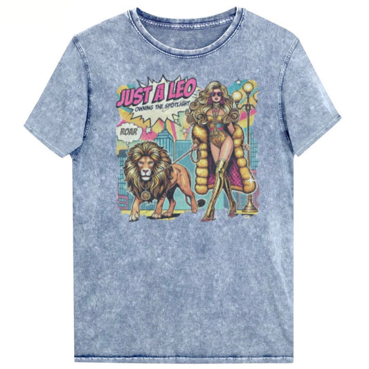 Flatlay of a unisex blue denim wash vintage t-shirt with a retro pop-art Leo graphic featuring a long curly haired blonde woman in a gold swimsuit, gold over the knee boots, gold medallion and long fur coat, walking a lion on a leash wearing a gold medallion, with a caption bubble 'Roar', with a city and round bulb street lights in the background captioned ‘Just a Leo, Owning the Spotlight'. Branded RedBlonde on inside neck and right shoulder