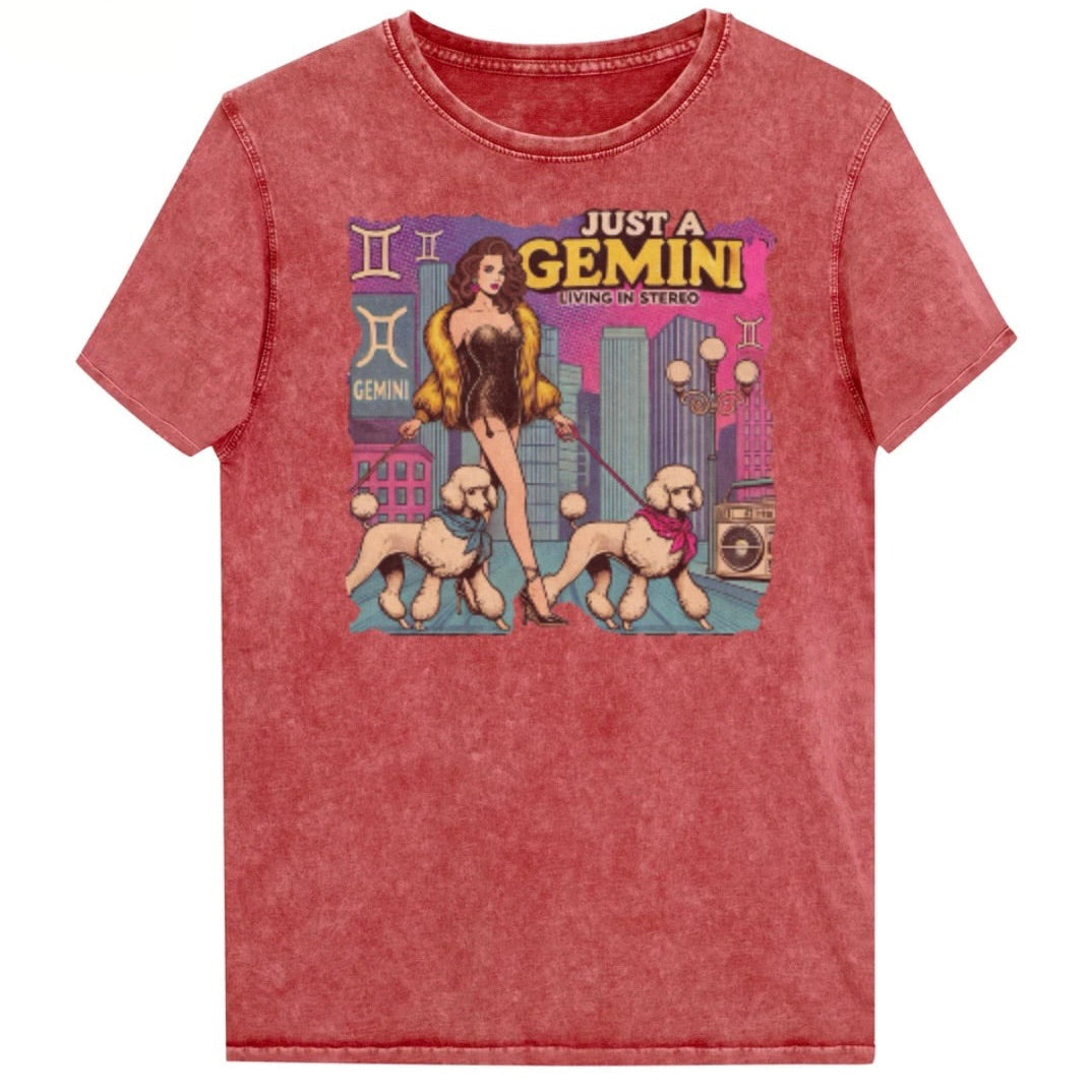 Flatlay of a unisex garnet red denim wash vintage t-shirt with a retro pop-art Gemini graphic featuring a brunette woman, in a short catsuit and fur coat walking two poodle dogs with neck scarfs with a city backdrop and a gettoblaster ‘Just a Gemini, Living in Stereo'. Branded RedBlonde in red on inside neck and right shoulder