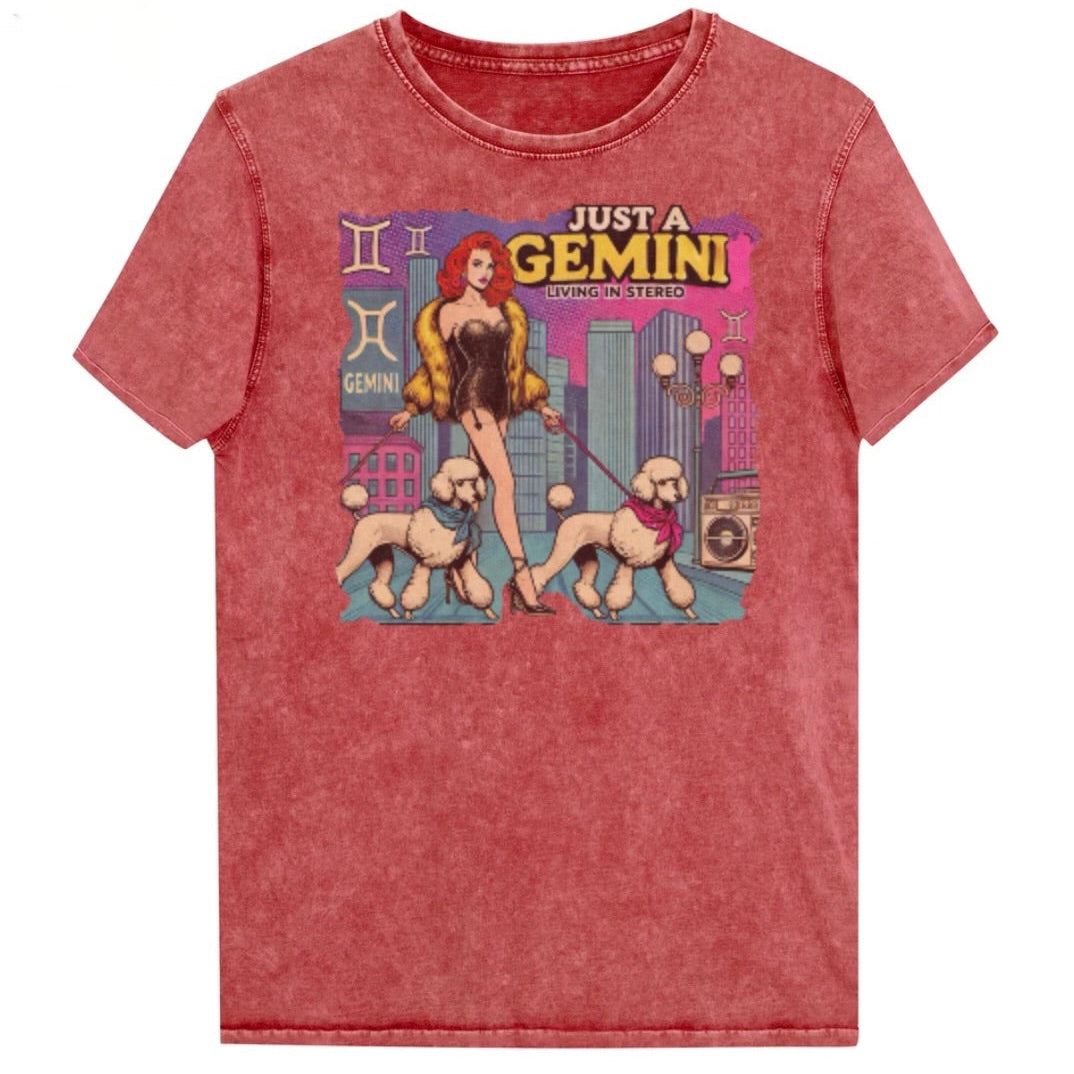 Flatlay of a unisex garnet red denim wash vintage t-shirt with a retro pop-art redhead Gemini graphic featuring a redhead woman, in a short catsuit and fur coat walking two poodle dogs with neck scarfs with a city backdrop and a gettoblaster ‘Just a Gemini, Living in Stereo'. Branded RedBlonde on inside neck and right shoulder