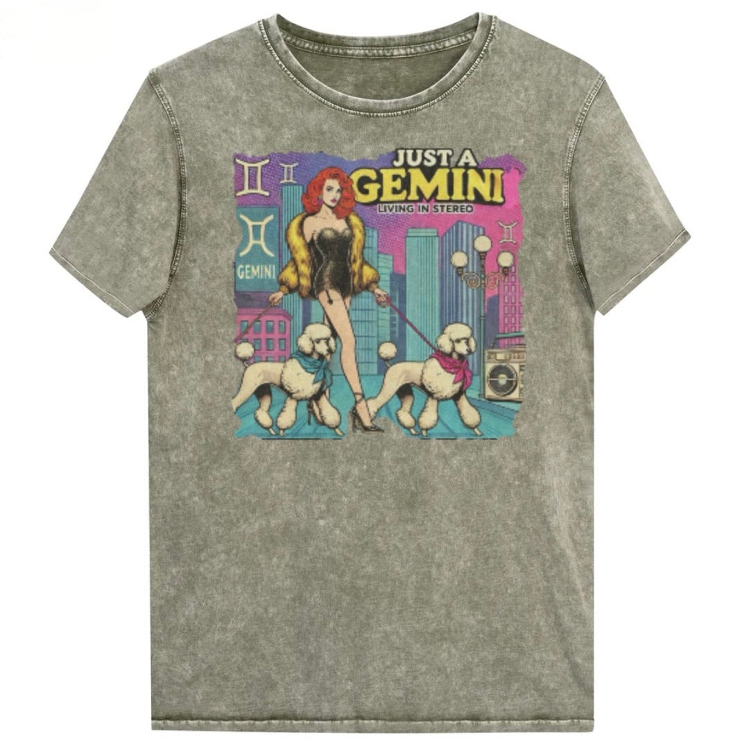 Flatlay of a unisex army green denim wash vintage t-shirt with a retro pop-art Gemini graphic featuring a redhead woman, in a short catsuit and fur coat walking two poodle dogs with neck scarfs with a city backdrop and a gettoblaster ‘Just a Gemini, Living in Stereo'. Branded RedBlonde on inside neck and right shoulder
