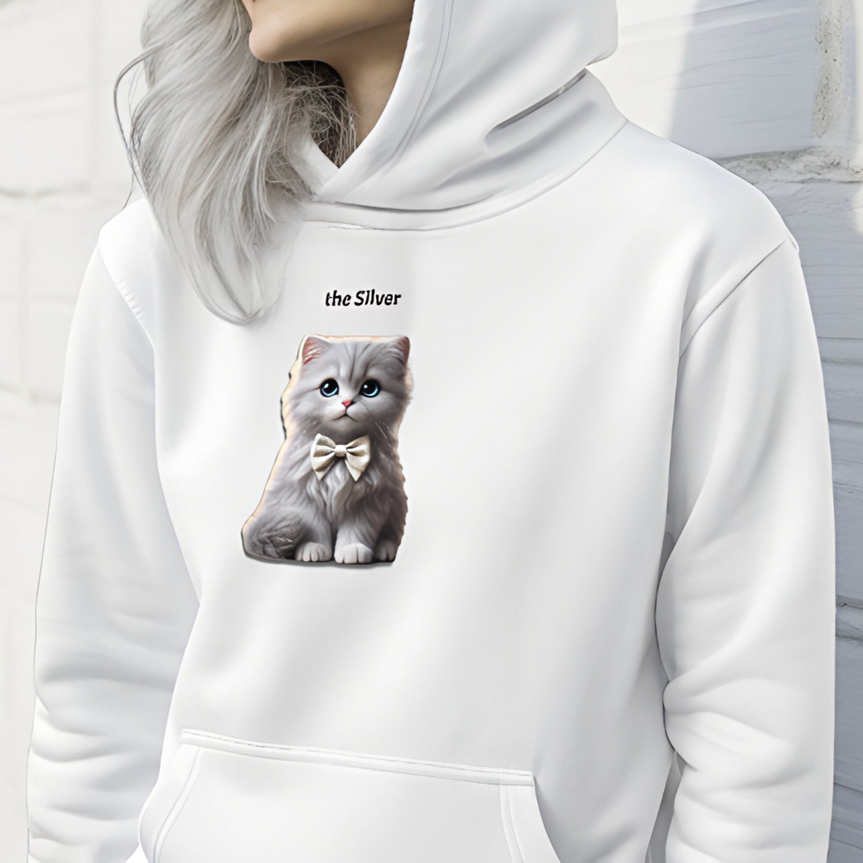 Model with silver hair wearing white relaxed fit unisex hoodie with a cute graphic of a silver kitten wearing a bow-tie and the words 'the Silver' linking to silver hair. Branded RedBlonde in red on inside neck and right cuff