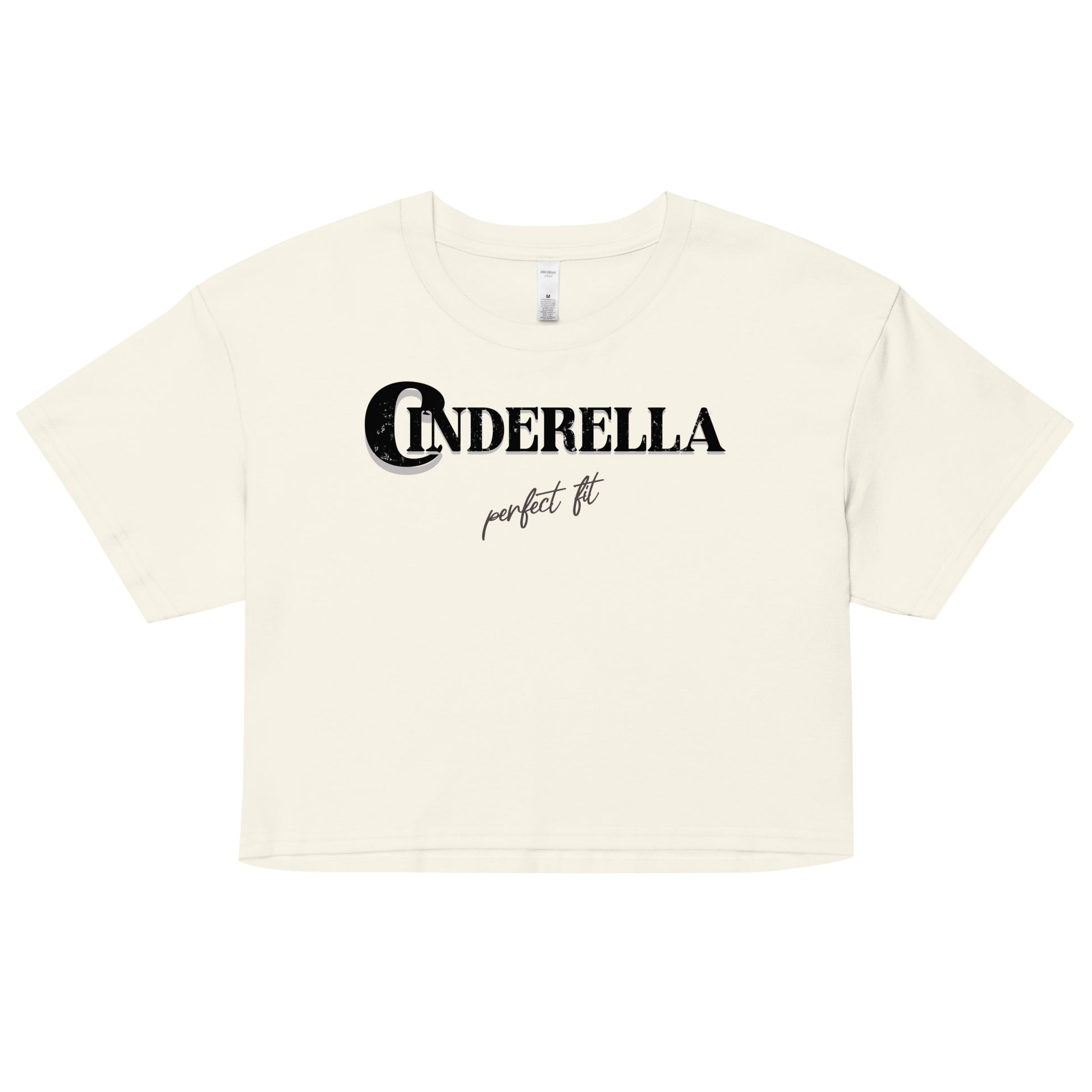 Natural-colored women’s crop top featuring black merger text that reads “Cinderella” with a decorative crescent moon incorporated into the letter C, and the phrase “perfect fit” written underneath in an elegant cursive script.