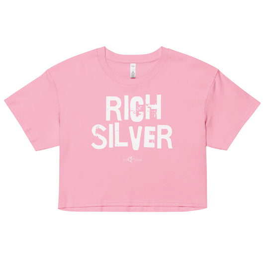 a pink coloured crop top with a relaxed fit, short sleeves, and a wide crew neckline. The front features bold white distressed lettering reading “RICH SILVER” with the RedBlonde signature logo underneath in white