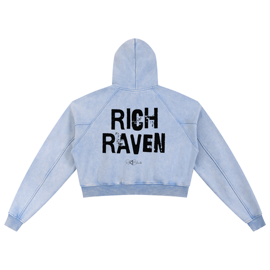 Back view of a cropped snow-wash pale blue hoodie with bold black “RICH RAVEN” Ed Gein font and the RedBlonde signature logo printed below.