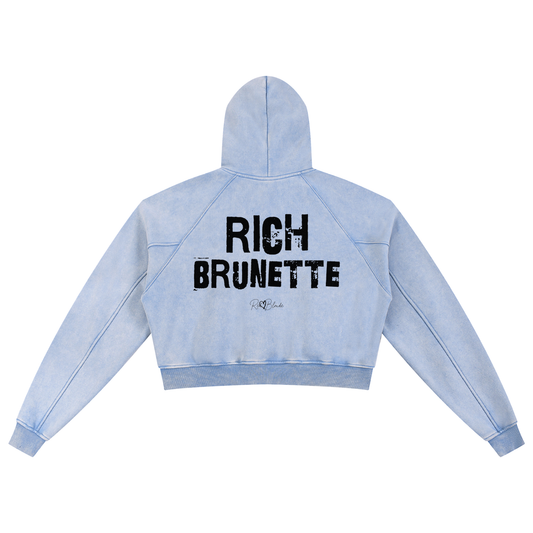 Back view of a cropped snow-wash pale blue hoodie with bold black “RICH BRUNETTE” Ed Gein font and the RedBlonde signature logo printed below.