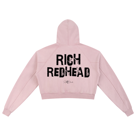 Back view of a cropped snow-wash pale pink hoodie with bold black “RICH REDHEAD” Ed Gein font and the RedBlonde signature logo printed below.