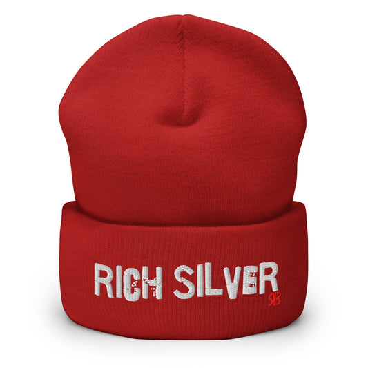 Red knitted beanie with the embroidered phrase “Rich Silver” in white script and a small red RB logo on the fold-over cuff, displayed against a clean white background.
