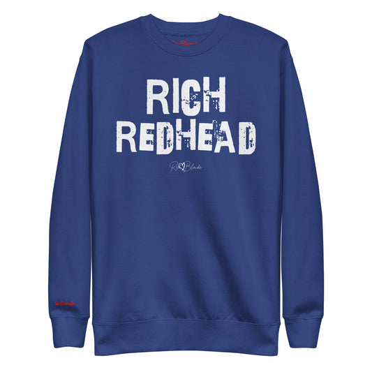 Royal Blue unisex premium sweatshirt with bold distressed white Ed Geinitext “RICH REDHEAD” on the front, featuring a subtle RedBlonde logo beneath the lettering and on the sleeve cuff and inside neck