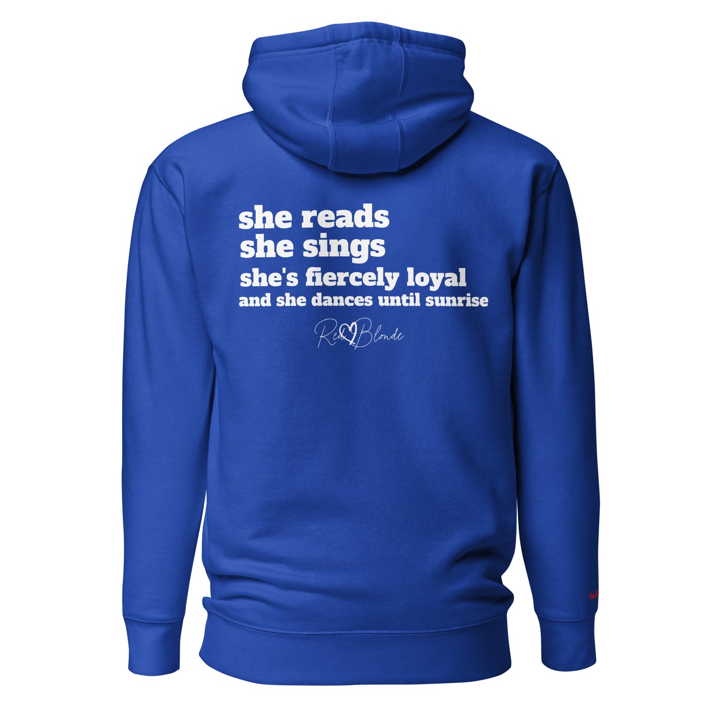Back view of a royal blue unisex hoodie featuring white text that reads, “she reads, she sings, she’s fiercely loyal, and she dances until sunrise,” with the RedBlonde logo printed underneath. The design conveys confidence and personality with a bold, uplifting message.