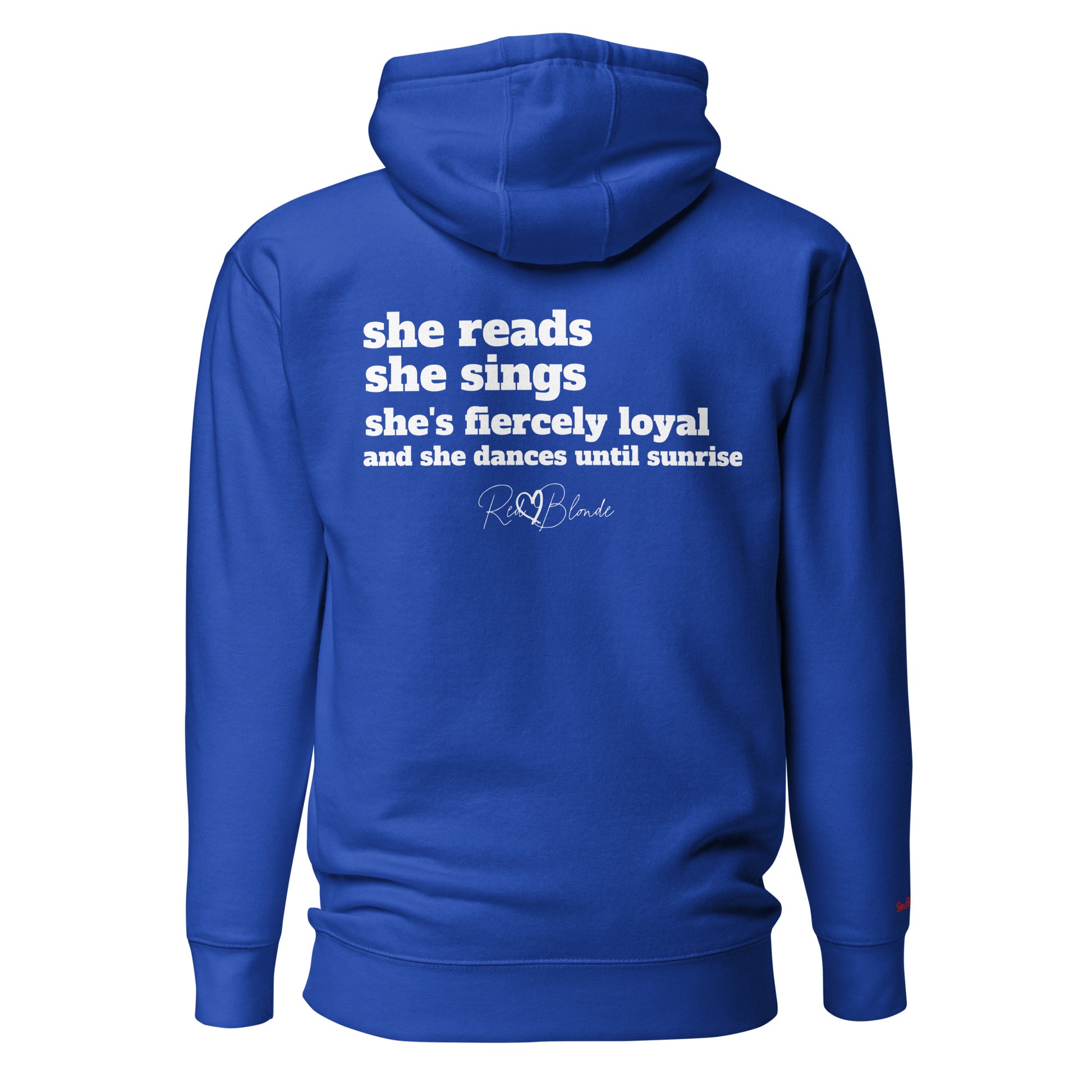 Back view of a royal blue unisex hoodie featuring white text that reads, “she reads, she sings, she’s fiercely loyal, and she dances until sunrise,” with the RedBlonde logo printed underneath. The design conveys confidence and personality with a bold, uplifting message.