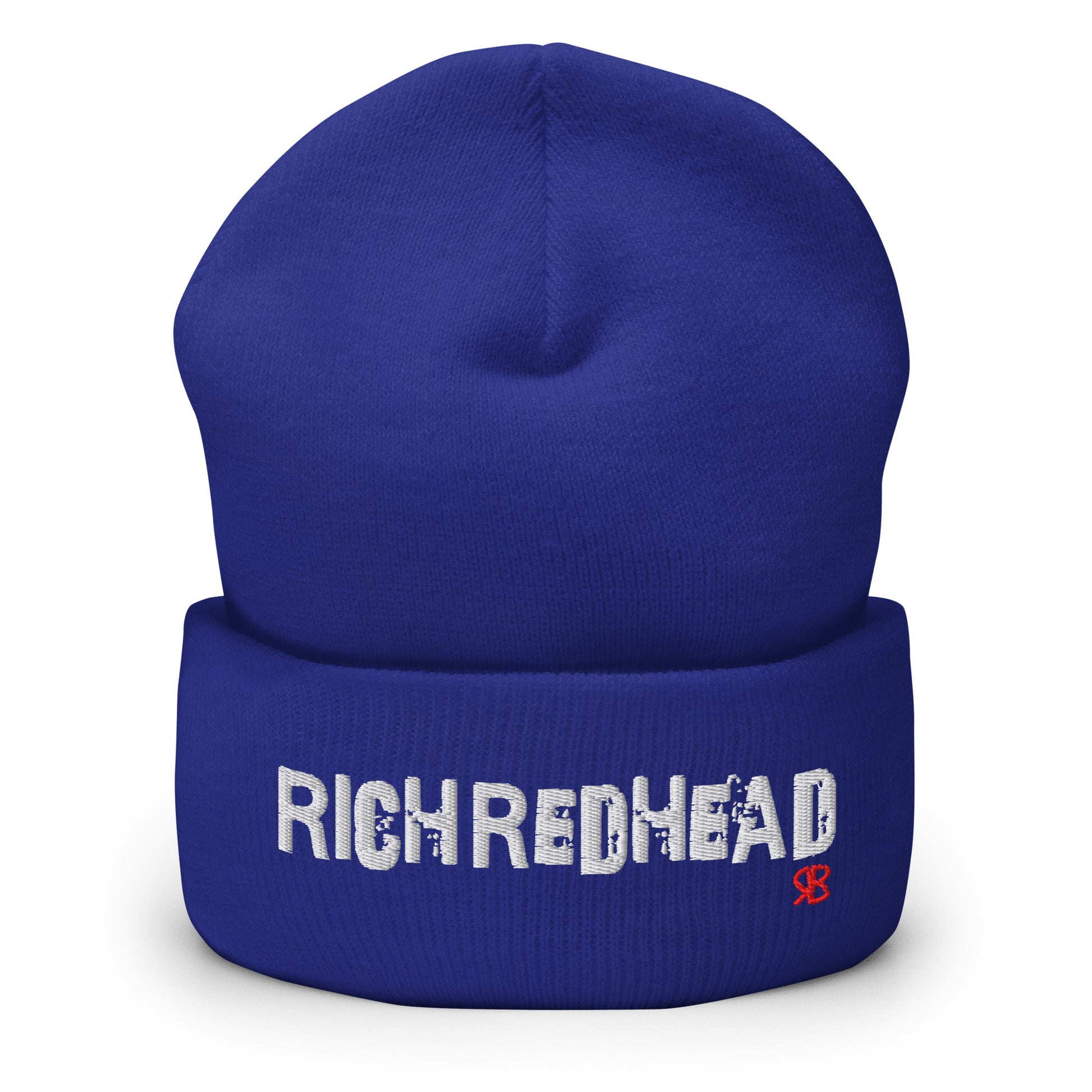 Royal blue cuffed beanie with the embroidered slogan “RICH REDHEAD” in bold white distressed-style lettering, featuring a small red “RB” RedBlonde logo on the right side of the fold. The beanie is shown upright against a clean white background.