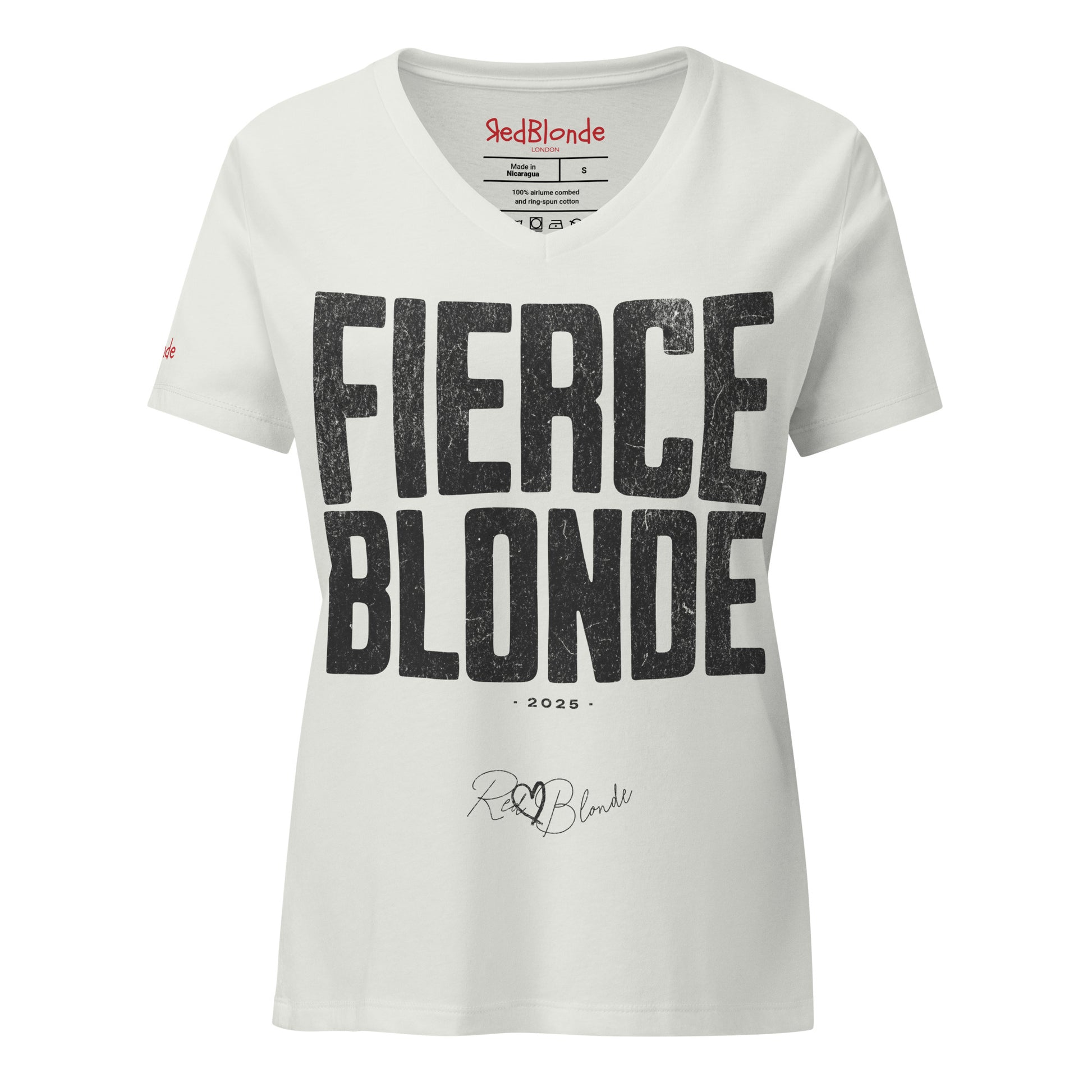Silver women’s V-neck T-shirt featuring the bold black distressed text “FIERCE BLONDE” in large North Road capital letters across the chest. Beneath the text, the year “2025” is printed in small type, with the “RedBlonde” brand signature logo below it. The inner collar shows the “RedBlonde” brand name in red along with sizing and care details, and “RedBlonde” is also printed in small red letters on the right sleeve.