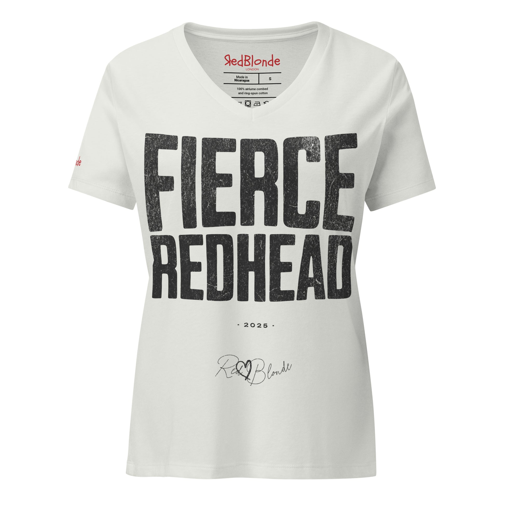 Silver women’s V-neck T-shirt featuring the bold black distressed text “FIERCE REDHEAD” in large North Road capital letters across the chest. Beneath the text, the year “2025” is printed in small type, with the “RedBlonde” brand signature logo below it. The inner collar shows the “RedBlonde” brand name in red along with sizing and care details, and “RedBlonde” is also printed in small red letters on the right sleeve.