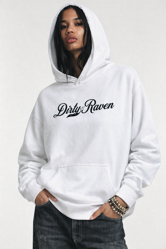 model wears a white oversized hoodie with kangaroo front pocket and ribbed cuffs and hem. Across the chest is black Milkstore 01 script text reading “Dirty Raven.”