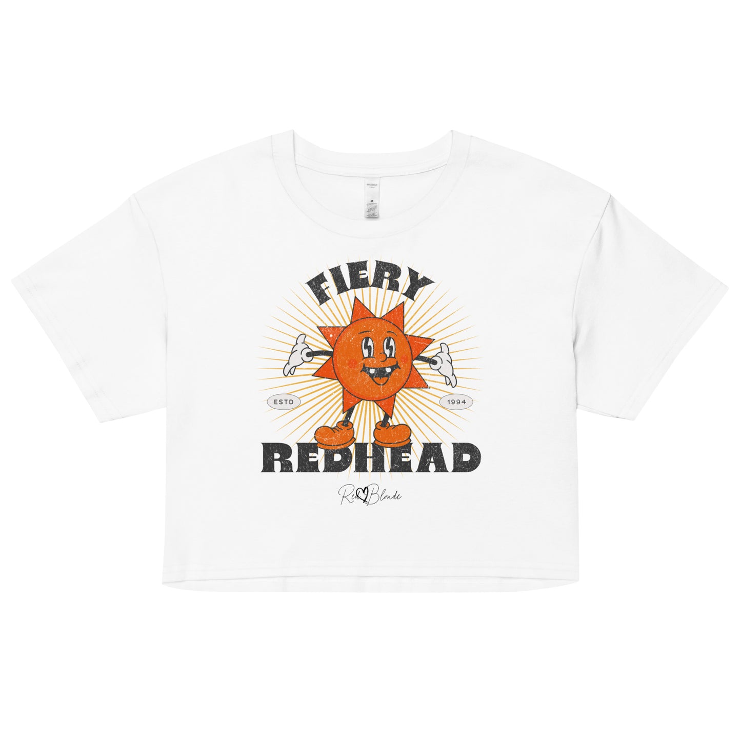 White women’s crop top with a bold retro graphic of a smiling orange cartoon sun character, surrounded by radiant sunbeams. The text reads ‘Fiery Redhead’ in distressed black Belzebuth lettering with small details including ‘ESTD 1994’ and the RedBlonde signature logo beneath."