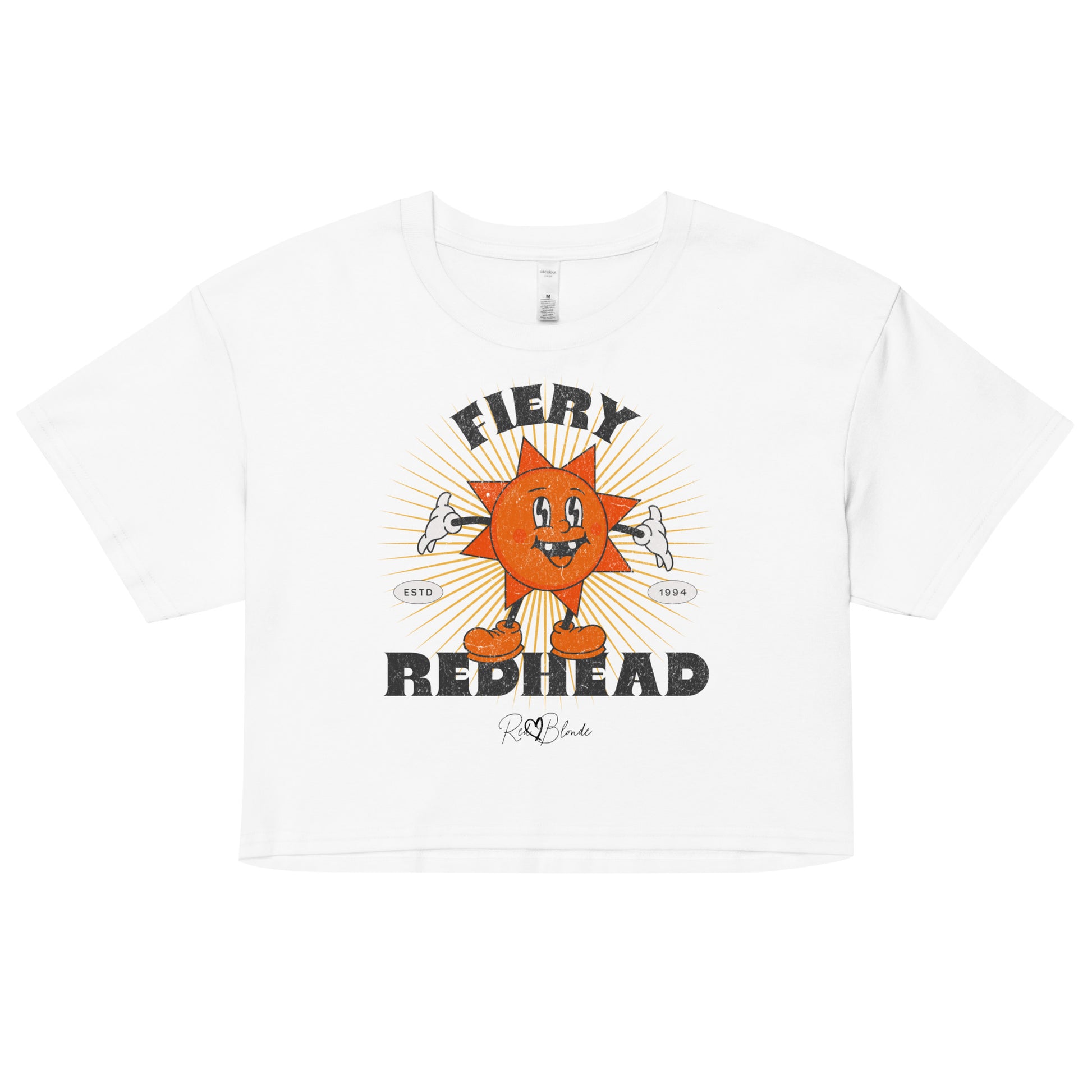White women’s crop top with a bold retro graphic of a smiling orange cartoon sun character, surrounded by radiant sunbeams. The text reads ‘Fiery Redhead’ in distressed black Belzebuth lettering with small details including ‘ESTD 1994’ and the RedBlonde signature logo beneath."