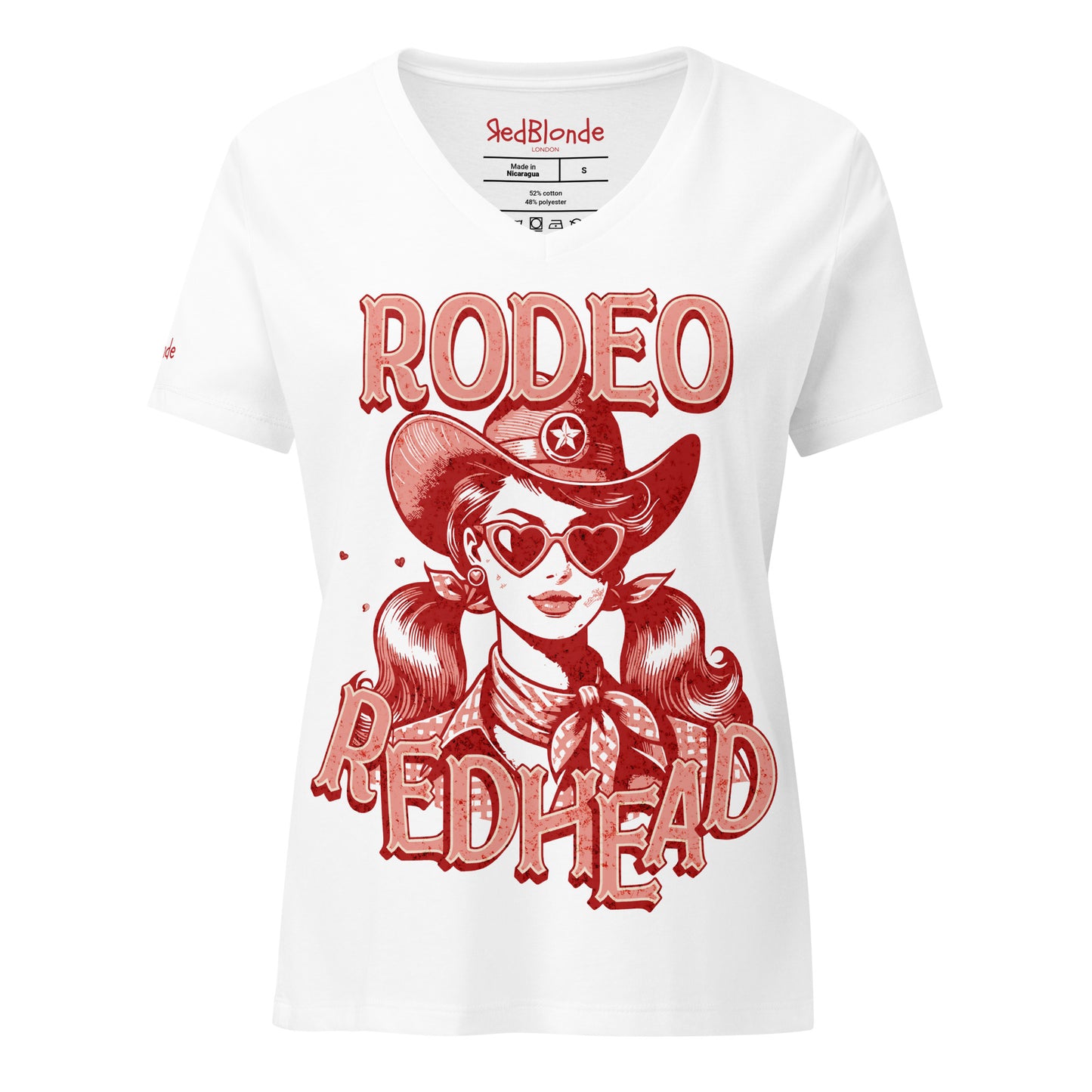 Women's white V-neck t-shirt featuring a bold red vintage illustration of a cowgirl with heart-shaped sunglasses and pigtails, wearing a wide-brimmed cowboy hat and scarf. Text reads "RODEO REDHEAD" in large Western-style lettering. Branded RedBlonde on inside neck and right sleeve.