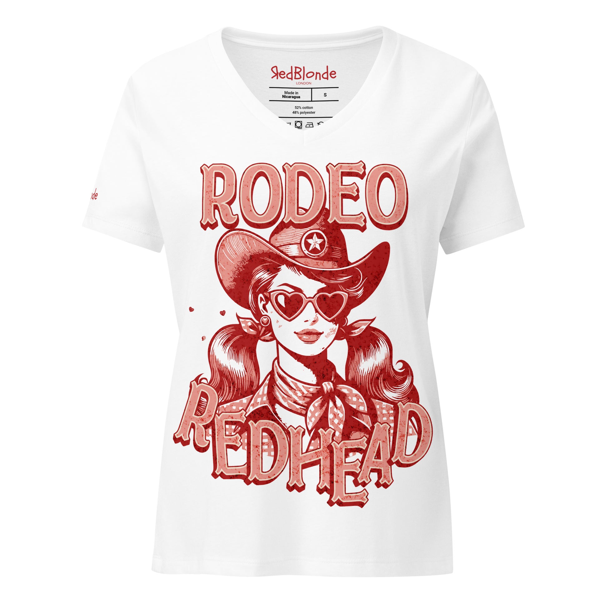 Women's white V-neck t-shirt featuring a bold red vintage illustration of a cowgirl with heart-shaped sunglasses and pigtails, wearing a wide-brimmed cowboy hat and scarf. Text reads "RODEO REDHEAD" in large Western-style lettering. Branded RedBlonde on inside neck and right sleeve.