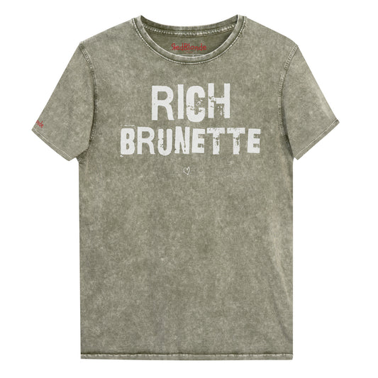 an army green acid-wash unisex denim T-shirt with a distressed vintage look. The shirt features the bold white text “RICH BRUNETTE” in a weathered Ed Gein font, and features the RedBlonde signature logo. The shirt has short sleeves, a crew neckline, and visible seam detailing for a rugged, casual style. Branded Redblonde on inside neck and right sleeve