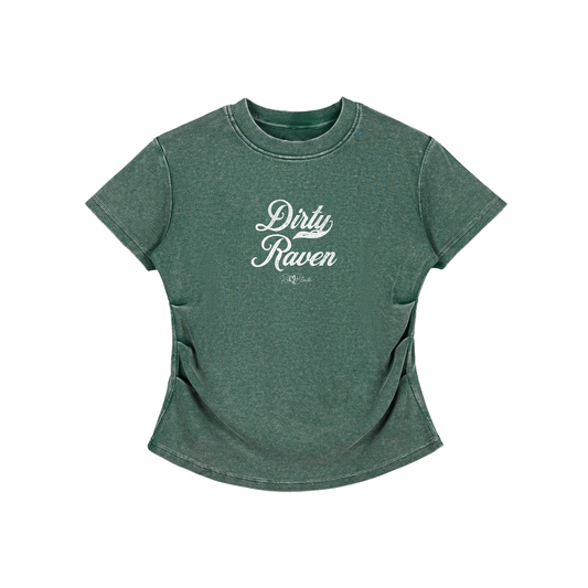 A fitted, short-sleeve green crewneck T-shirt laid flat on a white background. It has subtle ruching/contouring at the sides and a slightly curved hem. white script text across the chest reads “Dirty Raven,” in Milkstore 01 script with a small cursive “RedBlonde” logo beneath.