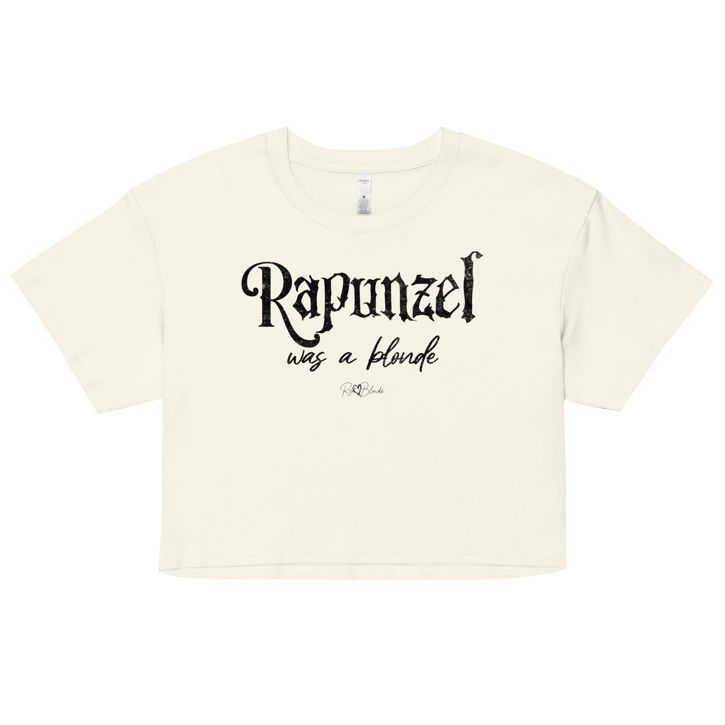 Natural-colored women’s crop top featuring black fairytale spiky text that reads “Rapunzel" and the phrase “was a blonde” written underneath in an elegant cursive script. signed off with the RedBlonde heart signature logo