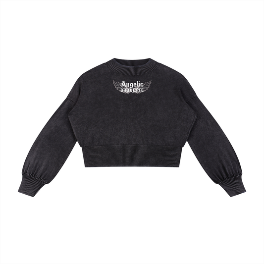 black mineral-wash cropped sweater with balloon sleeves, ribbed collar/cuffs/waistband, and a white “Angelic Brunette” wing graphic on the chest, shown on a white background.