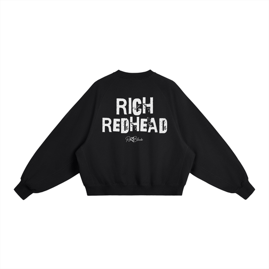 Black oversized dolman-sleeve sweatshirt shown from the back on a plain white background. It has a boxy, relaxed fit with dropped shoulders, ribbed crew neckline, ribbed cuffs, and a ribbed hem band. Centered on the back is a distressed white “RICH REDHEAD” Ed Gein graphic with a small “RedBlonde” script logo beneath.