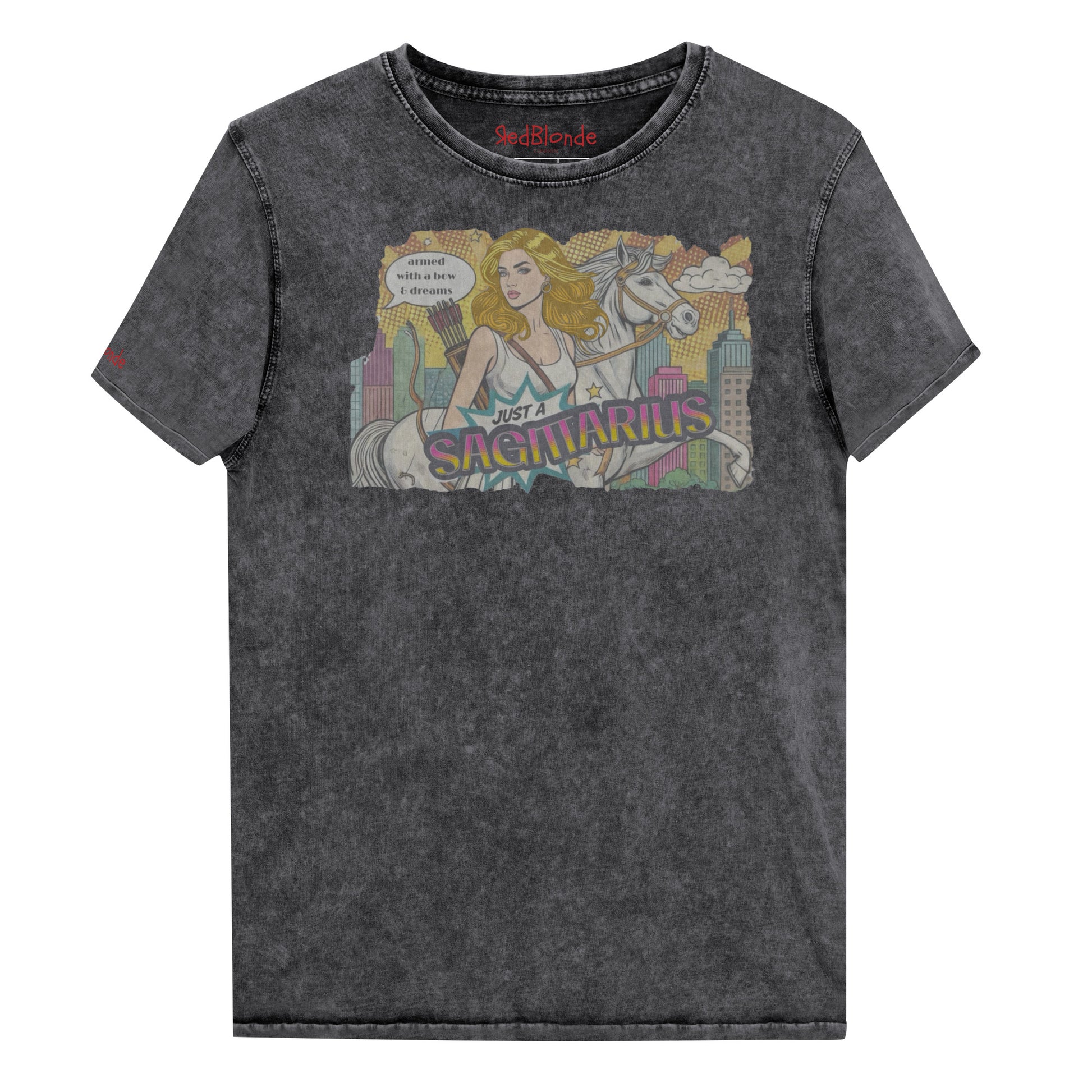 Flatlay of a unisex black denim wash vintage t-shirt with a retro pop-art Sagittarius graphic featuring a blonde woman, with bow & arrows, white stallion, and a city backdrop, captioned ‘Just a Sagittarius, armed with a bow & dreams'. Branded RedBlonde on the inside neck and right sleeve