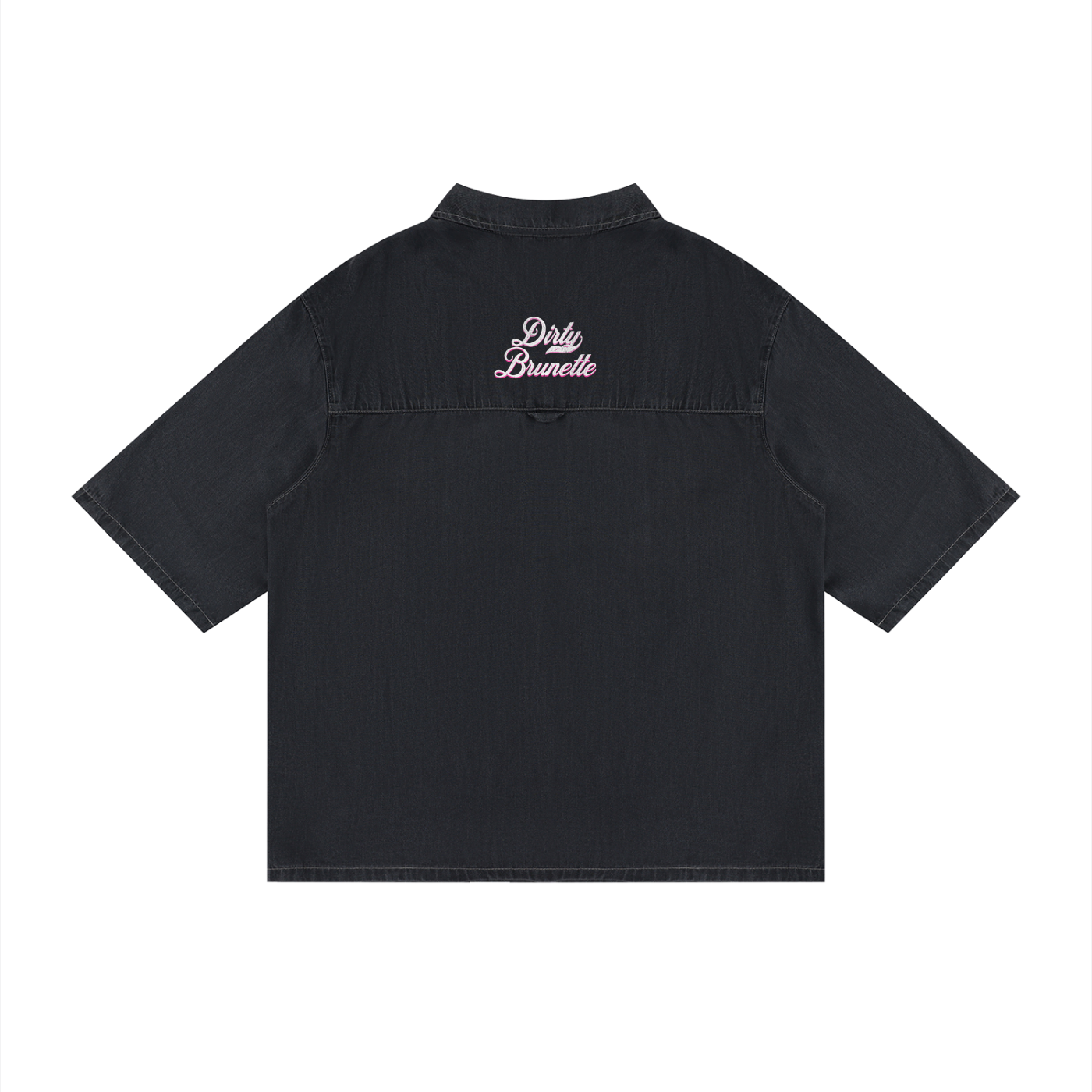 back view of a black, short-sleeve button-up shirt with a subtle faded finish and a small raised “Dirty Brunette” Milkstore script logo centered across the upper back.