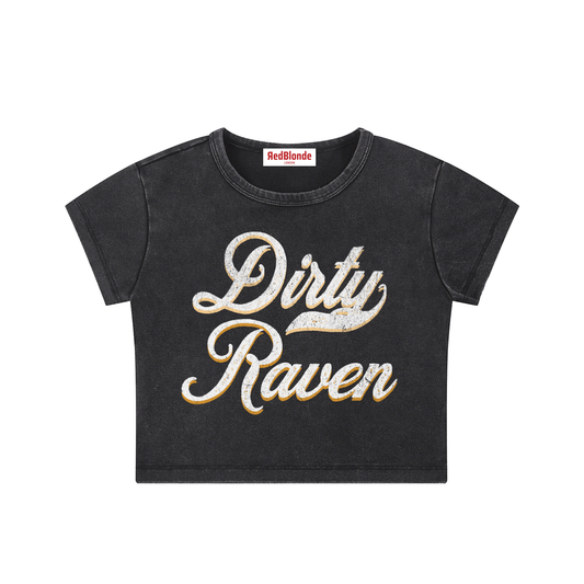 black short-sleeve crop T-shirt with large cursive “Dirty Raven” Milkstore text in white and yellow on the front, and a small “RedBlonde London” label at the neckline.
