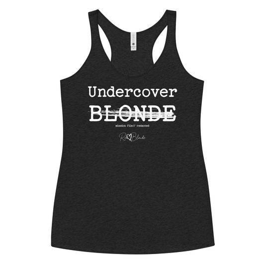 A black racerback tank featuring a bold white text reading “Undercover BLONDE” with “BLONDE” partially struck through by a horizontal white bar. Beneath it, smaller text says “mission file // redacted” along with a subtle RedBlonde logo. Branded RedBlonde London in red on the reverse