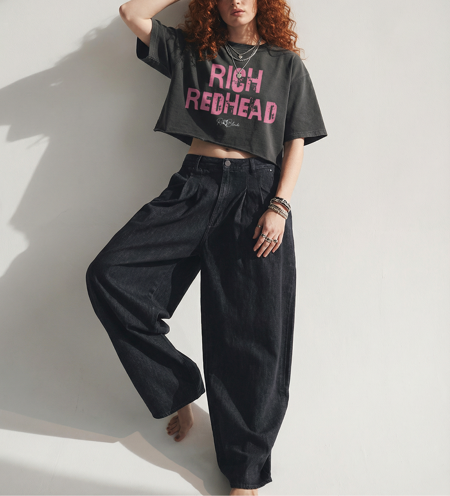 Black cropped T-shirt with oversized short sleeves and a bold pink “RICH REDHEAD” in Ed Gein font graphic on the front, plus a small RedBlonde script logo underneath.