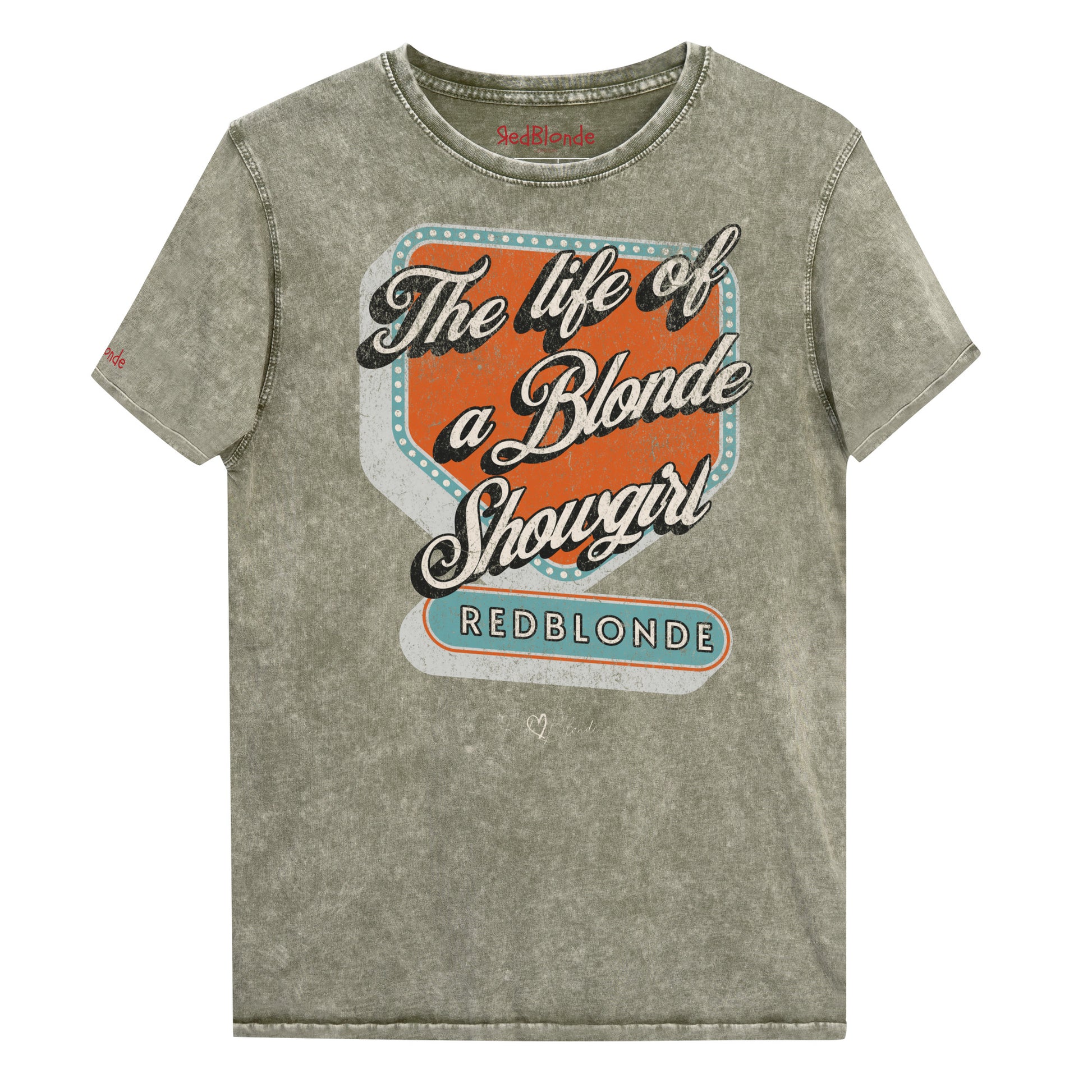 Vintage army green acid-wash unisex t-shirt with bold retro-style graphic text reading 'The life of a Blonde Showgirl' in white script over an orange and turquoise marquee design. The word 'RedBlonde' is displayed in turquoise block letters at the bottom, with subtle worn details giving the shirt a distressed, retro look." Branded redblonde on inside collar and right sleeve