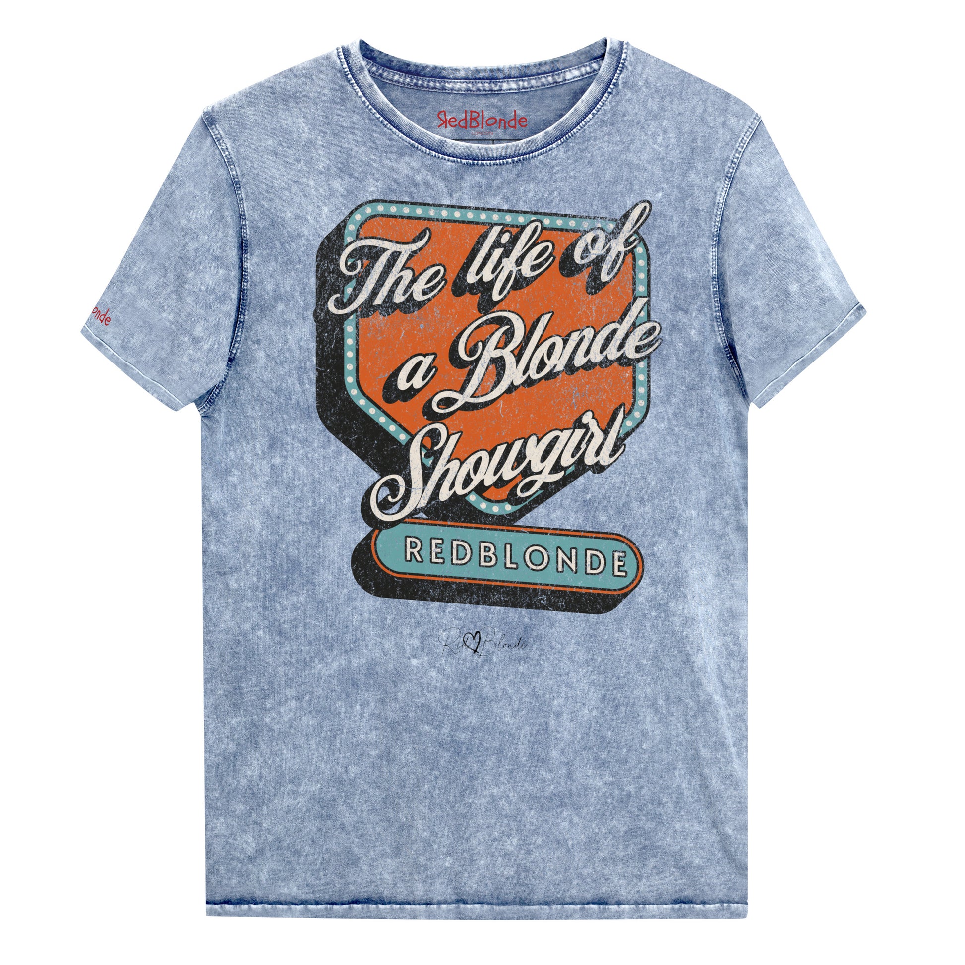 Vintage blue acid-wash unisex t-shirt with bold retro-style graphic text reading 'The life of a Blonde Showgirl' in white script over an orange and turquoise marquee design. The word 'RedBlonde' is displayed in turquoise block letters at the bottom, with subtle worn details giving the shirt a distressed, retro look." Branded redblonde on inside collar and right sleeve