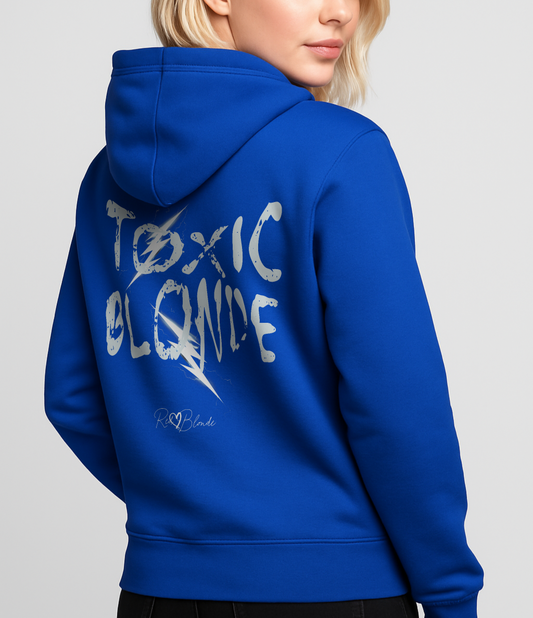 Blonde wears a royal blue unisex hoodie featuring bold distressed white Chainsaw Carnage text reading “Toxic Blonde” with lightning-style accents and the RedBlonde signature logo underneath. The design has an edgy, electric aesthetic.Branded RedBlonde in red on right sleeve
