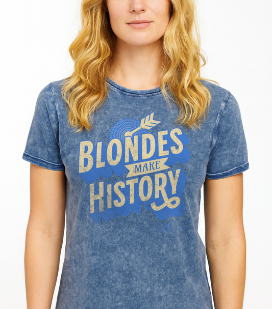 blonde wears a Blue acid-wash unisex T-shirt with bold vintage-style HT modern han sans lettering in blue that reads ‘Blondes Make History’, accented with an arrow graphic and decorative banner. Branded RedBlonde in red on inside neck and right sleeve