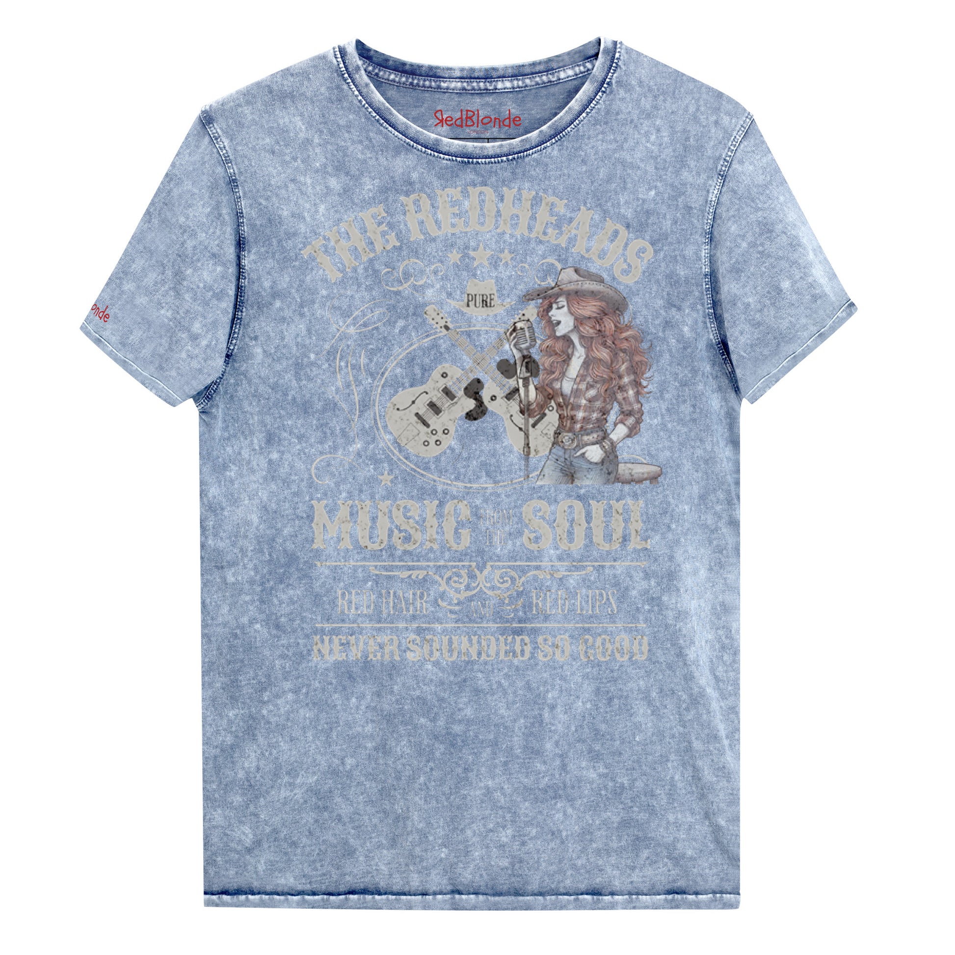 A blue denim wash unisex t-shirt with ‘THE REDHEADS’, ‘MUSIC FROM THE SOUL’, ‘RED HAIR AND RED LIPS’, and ‘NEVER SOUNDED SO GOOD’ written in Sancreek font features a graphic of a redheaded cowgirl singing with two guitars behind her. Branded RedBlonde London in red on inside neck and right sleeve 