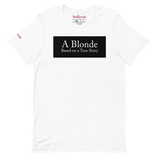 flatlay of a white unisex relaxed fit t-shirt with the slogan 'A Blonde. Based on a True Story' in white text in a black box graphic. Branded RedBlonde London in red on inside neck and right sleeve  