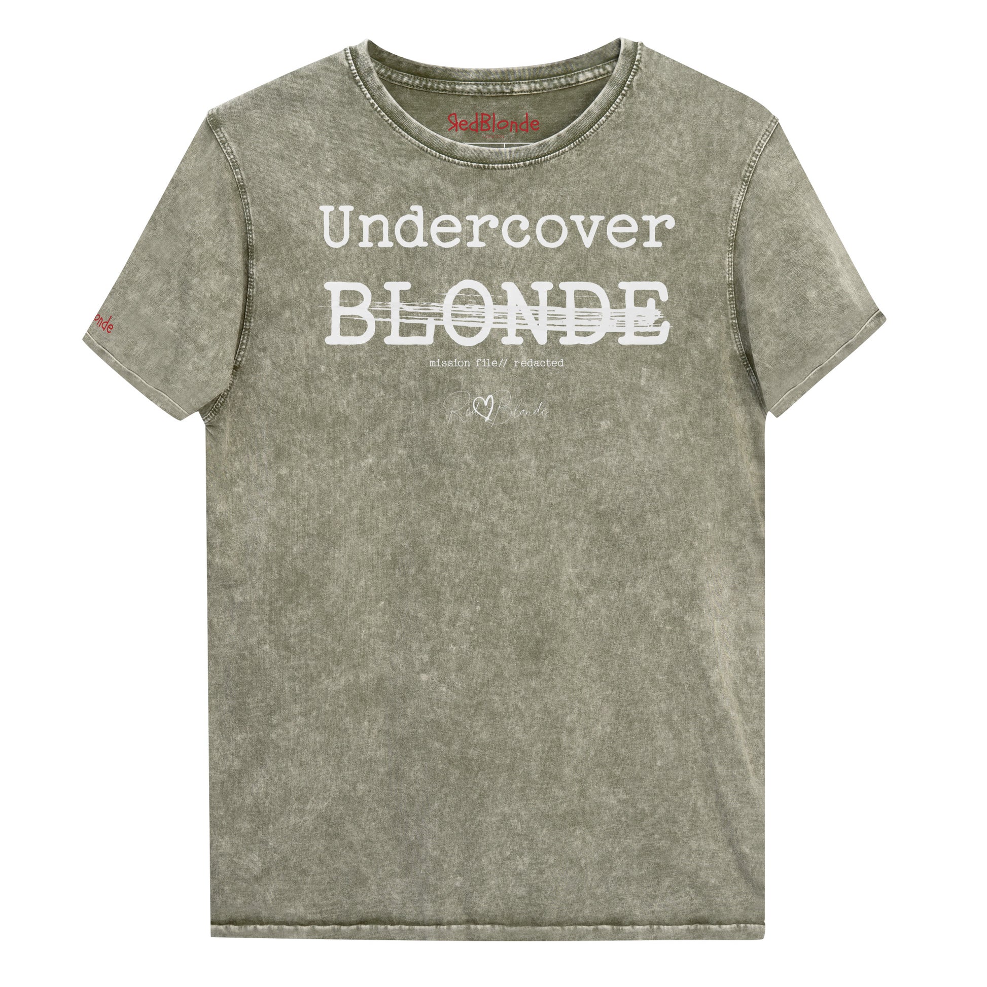 A dark army green unisex denim-style t-shirt with a vintage washed finish. The front features bold white text reading “Undercover BLONDE” with “BLONDE” partially struck through by a horizontal white bar. Beneath it, smaller text says “mission file // redacted” along with a subtle RedBlonde logo. The shirt has a classic crew neck and short sleeves with visible stitching for a rugged look. Branded RedBlonde London in red on inside neck and right sleeve