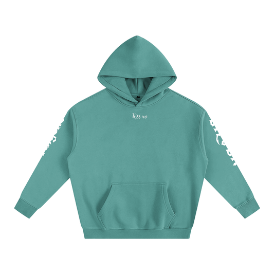 Front view of a medium green hoodie with Each sleeve features gothic New Rockstar font graphic text one sleeve says 'Angelic' and the other 'Silver' . 'Kiss me' features is small white text, center top 
