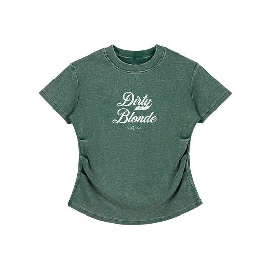 A fitted, short-sleeve green crewneck T-shirt laid flat on a white background. It has subtle ruching/contouring at the sides and a slightly curved hem. White script text across the chest reads “Dirty Blonde,” in Milkstore 01 script with a small cursive “RedBlonde” logo beneath.