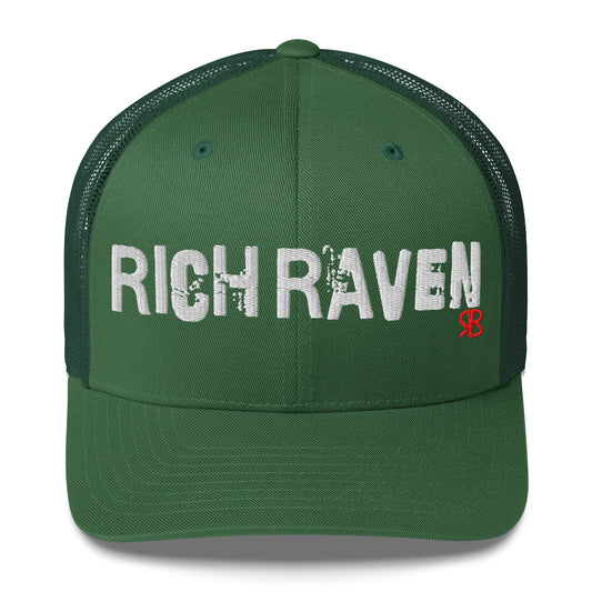 green mesh-back trucker cap with the bold distressed text “RICH RAVEN” embroidered in white across the front, and a small red “RB” logo detail beneath the text. The cap has a structured front panel and curved brim
