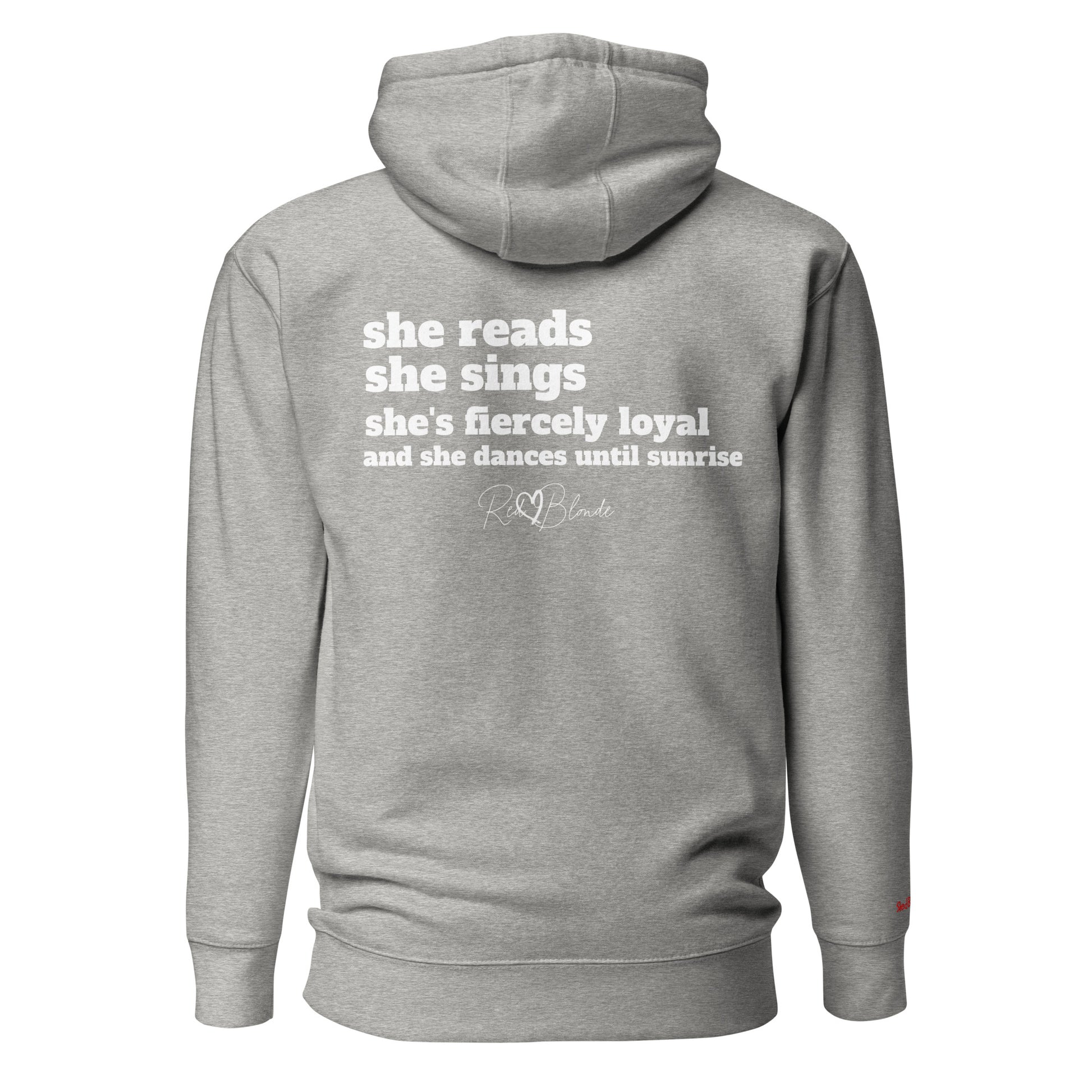 Back view of a grey unisex hoodie featuring white text that reads, “she reads, she sings, she’s fiercely loyal, and she dances until sunrise,” with the RedBlonde logo printed underneath. The design conveys confidence and personality with a bold, uplifting message.