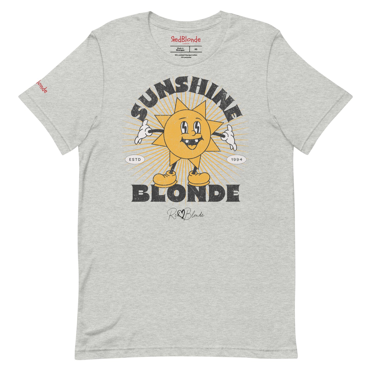 heather grey unisex crew neck t-shirt with a retro cartoon-style yellow sun character, smiling with open arms, surrounded by radiant sunbeams. The text reads ‘Sunshine Blonde’ in bold vintage Belzebuth lettering, with small details including ‘ESTD 1994’ and the RedBlonde signature logo beneath."
