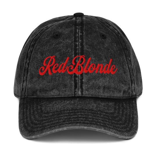 flatlay of vintage black denim wash effect baseball cap with the word 'RedBlonde' embroidered on the front in white adventure type script font 