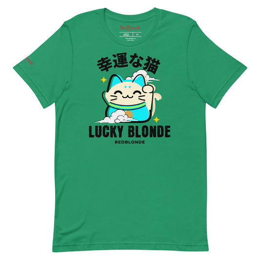 A kelly green unisex T-shirt featuring a cheerful maneki-neko (lucky cat) graphic in cream, turquoise, and black, with golden star accents. Above the cat are Japanese characters meaning “Lucky Cat.” Below the design, the text reads “LUCKY BLONDE” in bold black letters and “REDBLONDE” in smaller font. The T-shirt has a classic crew neckline and short sleeves. Branded RedBlonde on the inside neck and right sleeve